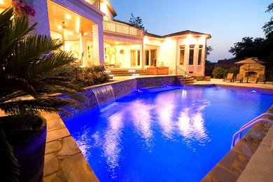 Foto de piscina con fuente mediterránea grande a medida en patio trasero con adoquines de piedra natural