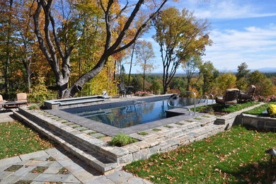 Modelo de piscinas y jacuzzis naturales tradicionales grandes rectangulares en patio trasero con adoquines de piedra natural