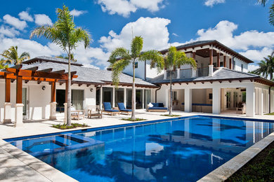 Ejemplo de casa de la piscina y piscina alargada costera grande rectangular en patio trasero con adoquines de piedra natural