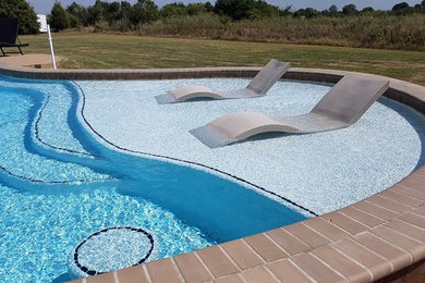 Diseño de piscina alargada tradicional a medida en patio trasero con adoquines de ladrillo