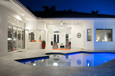 Ejemplo de piscina minimalista grande rectangular en patio trasero con adoquines de piedra natural