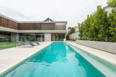 Ejemplo de piscinas y jacuzzis alargados modernos de tamaño medio a medida en patio trasero con adoquines de piedra natural