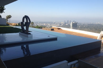 Large minimalist backyard tile and l-shaped infinity pool photo in Los Angeles