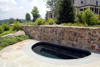 Imagen de piscina con fuente tradicional grande a medida en patio trasero con adoquines de piedra natural