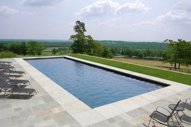 Ejemplo de piscina alargada clásica grande rectangular en patio trasero con suelo de baldosas
