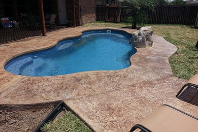 Inspiration for a medium sized back custom shaped natural swimming pool in Austin with a water feature and natural stone paving.