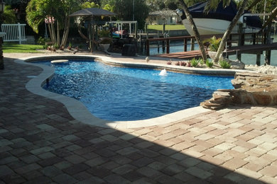 Ejemplo de piscina a medida en patio trasero con adoquines de hormigón