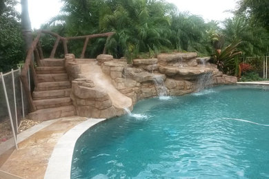 Example of a large island style backyard stone and custom-shaped natural water slide design in Miami