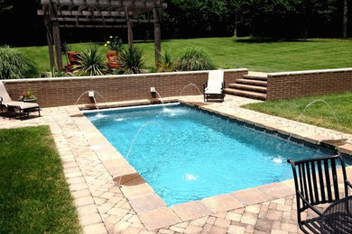 Modelo de piscina con fuente clásica renovada pequeña rectangular en patio trasero con adoquines de hormigón