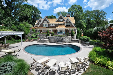 Foto de piscina alargada clásica extra grande redondeada en patio trasero con adoquines de hormigón