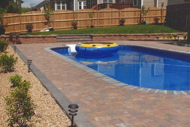 Diseño de piscina alargada clásica a medida en patio trasero con adoquines de ladrillo