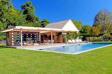 Immagine di una grande piscina monocorsia contemporanea rettangolare dietro casa con una dépendance a bordo piscina e lastre di cemento