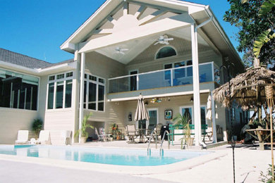 Diseño de piscina alargada clásica grande rectangular en patio trasero con adoquines de hormigón
