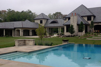 Diseño de piscina infinita tradicional grande a medida en patio trasero con adoquines de piedra natural