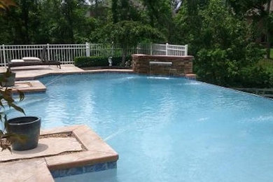 This is an example of a large back custom shaped infinity swimming pool in Cincinnati with a water feature.