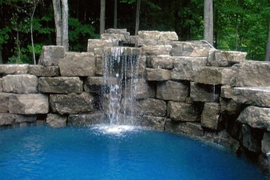 Diseño de piscina con fuente alargada tradicional de tamaño medio a medida en patio trasero con granito descompuesto