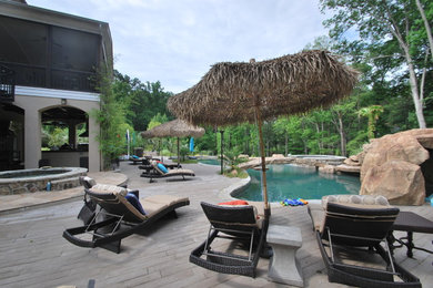 Diseño de piscina con fuente natural exótica grande a medida en patio trasero con adoquines de hormigón