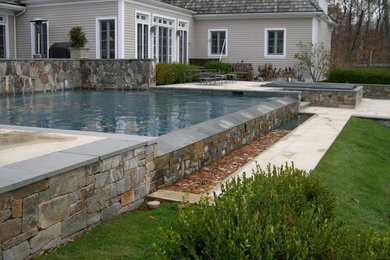 Modelo de piscina natural actual de tamaño medio rectangular en patio trasero con adoquines de piedra natural