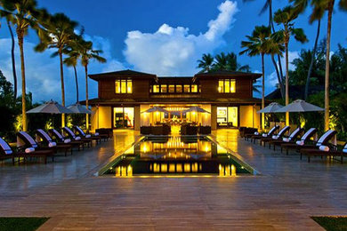 Diseño de piscina alargada tropical grande rectangular en patio trasero con entablado