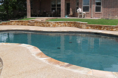 Example of a backyard concrete and custom-shaped pool design in Dallas