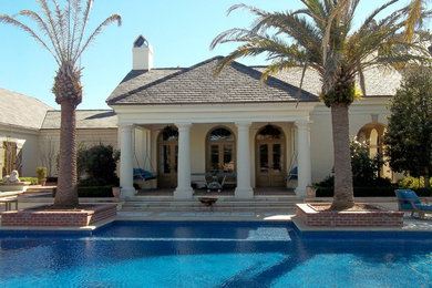 Modelo de casa de la piscina y piscina alargada tradicional de tamaño medio rectangular en patio trasero con adoquines de hormigón