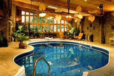 This is an example of a medium sized contemporary indoor custom shaped lengths swimming pool in Other with natural stone paving and a pool house.