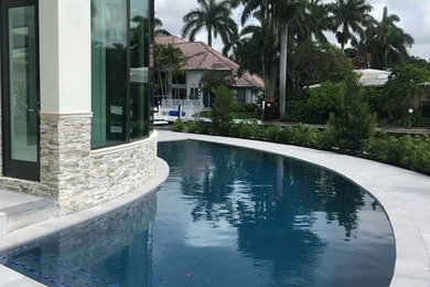 Mid-sized trendy side yard concrete paver and custom-shaped pool photo in Miami