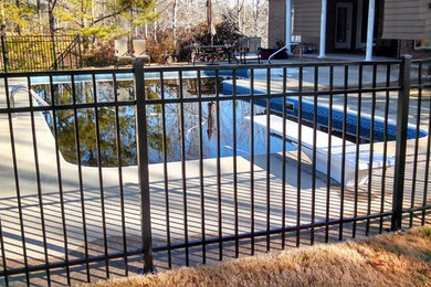 Imagen de piscina natural clásica de tamaño medio rectangular en patio trasero con losas de hormigón