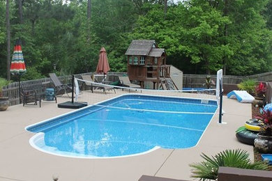 Ejemplo de piscina alargada clásica de tamaño medio a medida en patio trasero con losas de hormigón