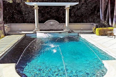 Modelo de piscina con fuente alargada tradicional grande rectangular en patio trasero con suelo de hormigón estampado