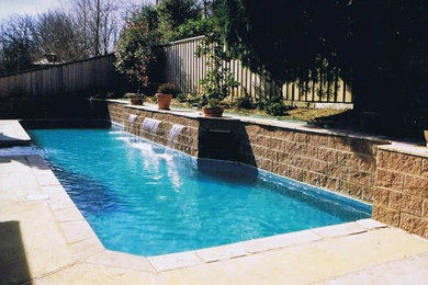 Modelo de piscina con fuente alargada contemporánea grande a medida en patio trasero con adoquines de hormigón
