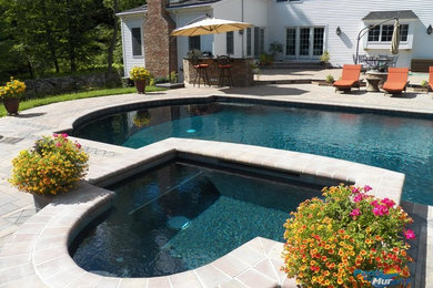 Ejemplo de piscinas y jacuzzis alargados clásicos grandes rectangulares en patio trasero con suelo de baldosas
