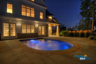 Imagen de piscina alargada clásica de tamaño medio a medida en patio trasero con adoquines de hormigón