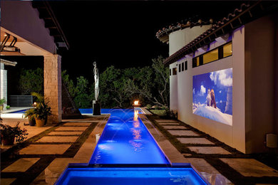 Immagine di una grande piscina monocorsia tradizionale a "L" dietro casa con fontane e lastre di cemento