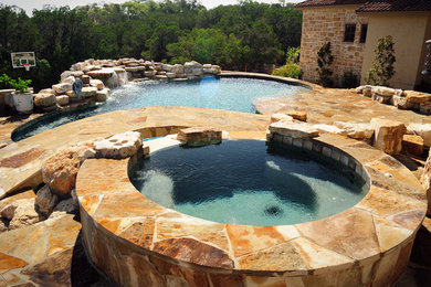 Modelo de piscina con fuente natural mediterránea grande a medida en patio trasero con adoquines de piedra natural