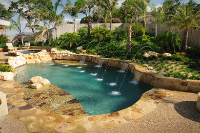 Ejemplo de piscina con fuente natural de estilo americano grande a medida en patio trasero con adoquines de piedra natural