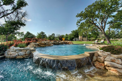 Foto de piscina con fuente alargada clásica de tamaño medio a medida en patio trasero con adoquines de piedra natural
