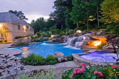 Modelo de piscina natural clásica de tamaño medio en patio trasero con adoquines de piedra natural