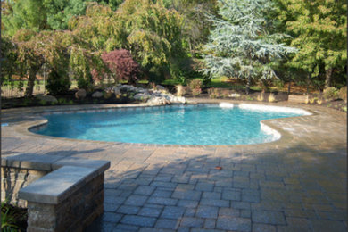 Ejemplo de piscina grande a medida en patio trasero con adoquines de piedra natural