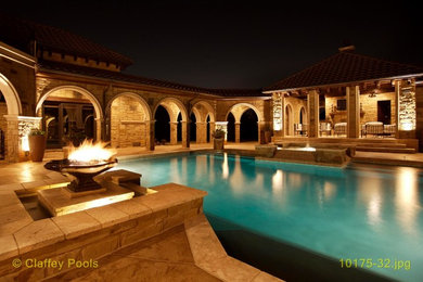 Ejemplo de casa de la piscina y piscina extra grande a medida en patio trasero con adoquines de piedra natural