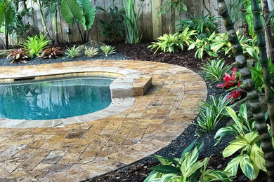 Diseño de piscina exótica de tamaño medio a medida en patio trasero con adoquines de hormigón