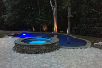 Diseño de piscinas y jacuzzis alargados clásicos de tamaño medio a medida en patio trasero con adoquines de ladrillo