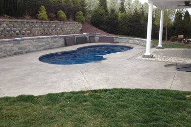 Ejemplo de piscina mediterránea de tamaño medio en patio trasero con losas de hormigón