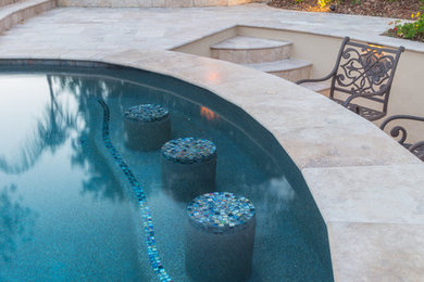 Imagen de piscina con fuente mediterránea grande a medida en patio trasero con suelo de baldosas