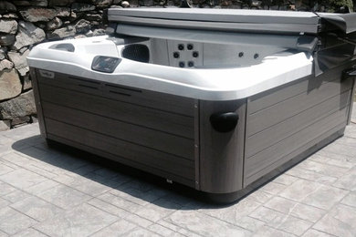 Ejemplo de piscinas y jacuzzis elevados clásicos pequeños rectangulares en patio trasero con suelo de hormigón estampado