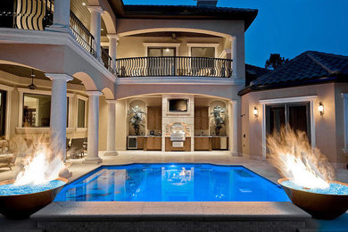 Ejemplo de piscina con fuente natural de estilo americano de tamaño medio rectangular en patio trasero con adoquines de piedra natural
