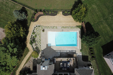 Imagen de piscina alargada tradicional grande rectangular en patio trasero con adoquines de hormigón