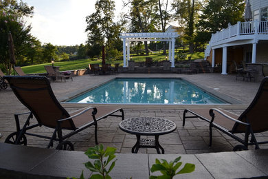 Ejemplo de piscina tradicional de tamaño medio rectangular en patio trasero con adoquines de hormigón