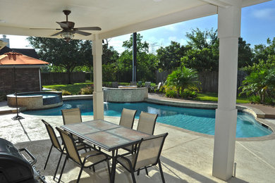 Großer Moderner Schwimmteich hinter dem Haus in individueller Form mit Wasserspiel und Natursteinplatten in Houston