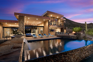 Huge trendy backyard rectangular and stone infinity pool fountain photo in Phoenix